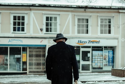一个穿着黑外套的人白天在积雪覆盖的地面上行走